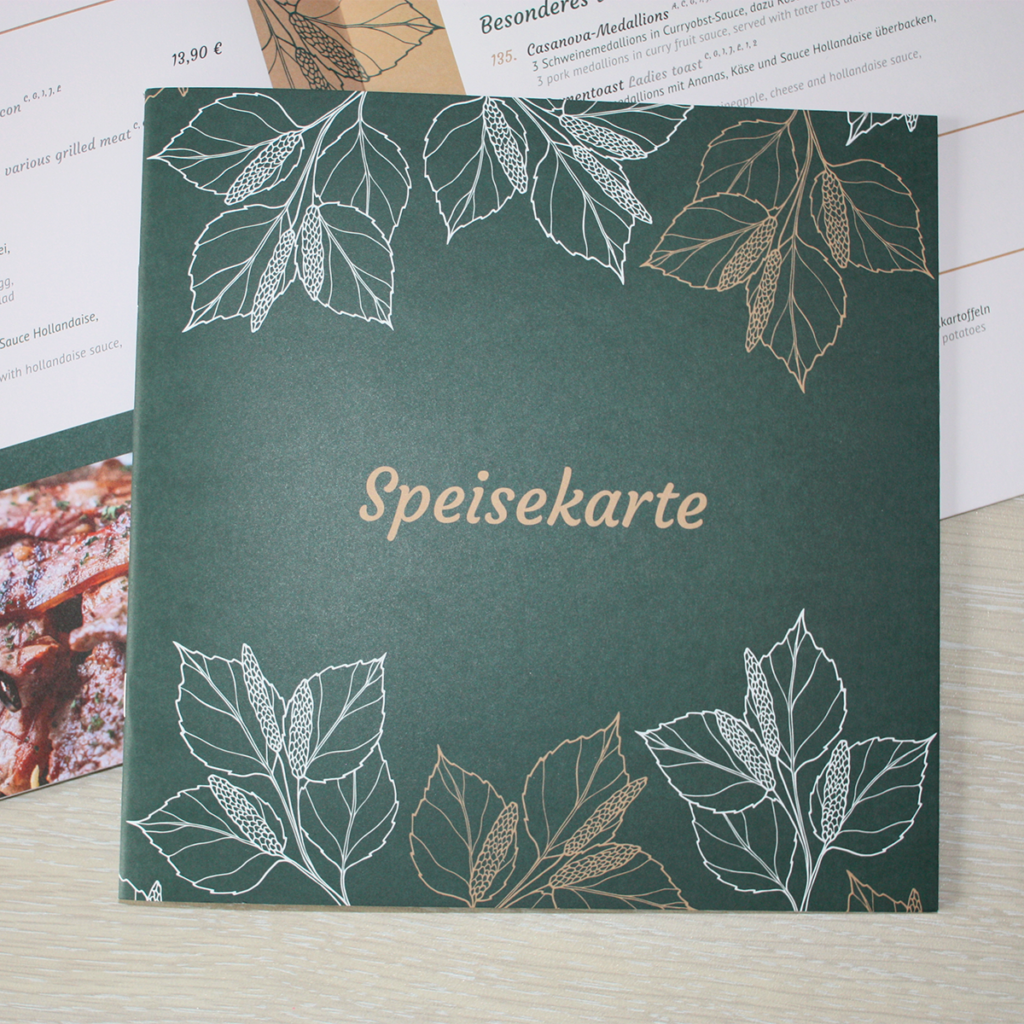 Speisekarte in dunkelgrün, weiß und beige mit zarten Blattern am Rand - gedruckt auf mattem Papier